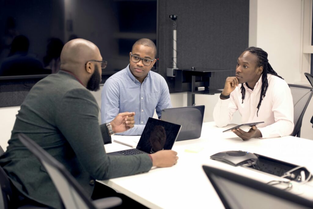 Equipe composta por três homens negros debate benefícios da substituição tributária para empresas.